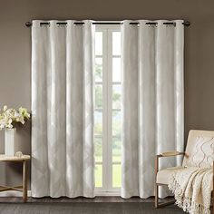 a living room with white curtains and a chair in front of a window that is open