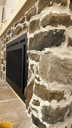 there is a fireplace built into the side of a stone wall in this room with yellow buckets on the floor