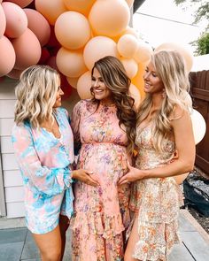 three beautiful women standing next to each other in front of balloons and balloon archs