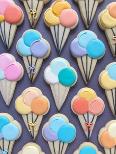 decorated cookies in the shape of ice cream cones with balloons and bows on them are displayed against a purple background