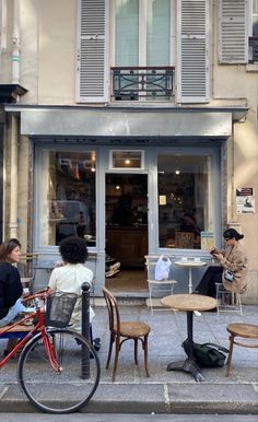 three people sitting at tables in front of a store