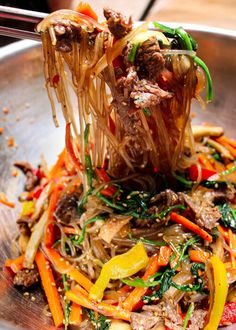 a metal bowl filled with noodles and veggies