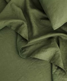 a close up view of a bed with green sheets and pillow cases on top of it