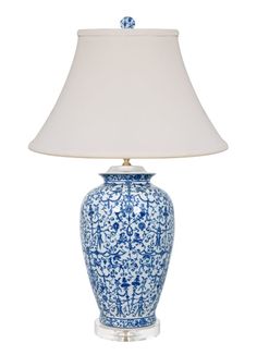 a blue and white vase with a light on it's side next to a lamp