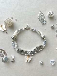 a silver bracelet with charms and leaves on it next to other jewelry items that include beads