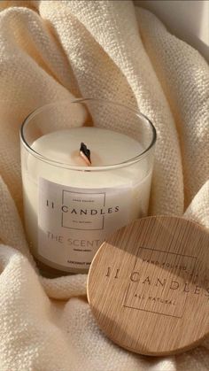 a candle sitting on top of a white blanket next to a wooden coaster that reads the scent of london