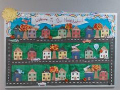 a welcome to our neighborhood bulletin board with houses and rainbows on the top, in front of a gray wall