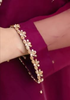 a close up of a person wearing a purple dress with gold jewelry on their arm