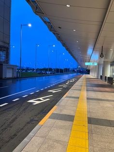 an empty airport terminal at night with no people on the sidewalk or in front of it