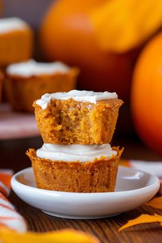 two cupcakes sitting on top of a white plate next to an orange pumpkin