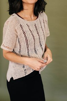 a woman is smiling while wearing a knitted sweater