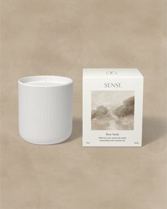 a white candle sitting on top of a table next to a box with the label sense