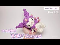 a crocheted purple and white stuffed animal on top of someone's hand