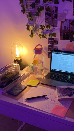 an open laptop computer sitting on top of a desk next to a lamp and papers