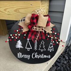 a merry christmas sign with burlocks and bows hanging from the front porch door