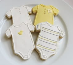 three decorated cookies on a white plate with yellow onesuits and one ducky