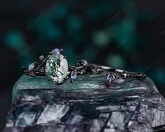 a close up view of an engagement ring on top of a rock with green leaves