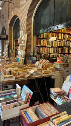 many books are stacked on tables in front of an old building with arched doorways