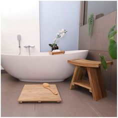 a white bath tub sitting next to a wooden stool