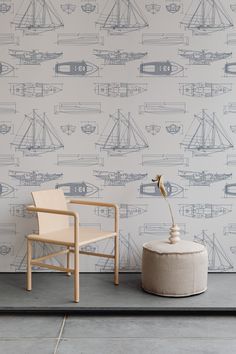 a chair and ottoman in front of a wall with boats on it