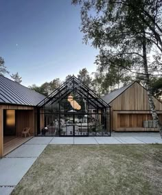 a glass house in the middle of a grassy area with wooden walls and roofing