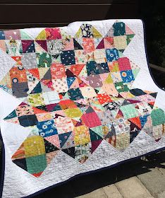 a colorful quilt is displayed on a bench