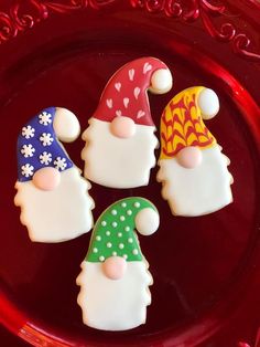 three decorated cookies sitting on top of a red plate with snowmen and gnome hats