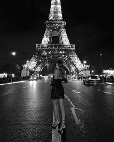 a woman standing in front of the eiffel tower at night with her hand on her hip