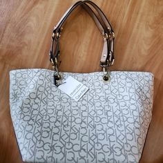 New Calvin Klein Tote Bag With Tag *Authentic* Cream/Beige/Brown/Gold Detachable Handles Reversible Inside Out Tote To Bucket Bag Magnetic Closure 18" L Top 11" L Bottom 11" H Condition Excellent New With Some Minor Scratches On Attachment Of The Handles. Never Been Used. Calvin Klein Adjustable Strap Shoulder Bag, Beige Satchel With Branded Hardware For Daily Use, Calvin Klein Satchel With Detachable Strap For Everyday, Chic Calvin Klein Shoulder Bag With Adjustable Strap, Trendy Beige Bag With Branded Hardware, Calvin Klein Top Handle Shoulder Bag, Calvin Klein Shoulder Bag With Adjustable Strap For Shopping, Casual Beige Bag With Branded Hardware, Calvin Klein Rectangular Bag With Branded Hardware