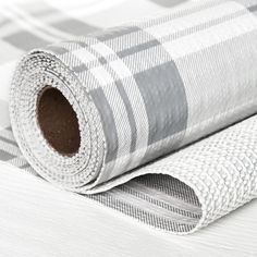 a white and grey checkered wallpaper roll laying on top of a bed sheet