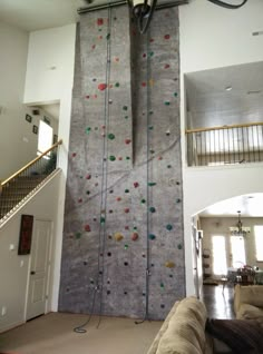 a living room with a climbing wall in the middle and stairs leading up to it