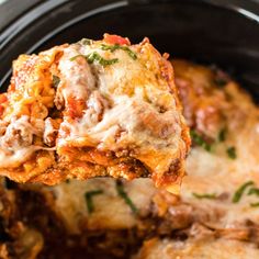 a spoon full of lasagna casserole being lifted from the slow cooker