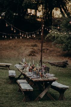 an outdoor dinner table set up with candles and place settings for the guests to sit at