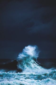 a large wave crashing into the ocean on a stormy day