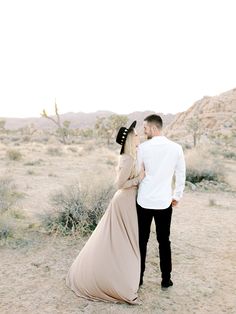 a man and woman are standing in the desert