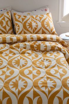 an orange and white comforter set on a bed in a room with a window