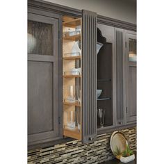 a kitchen with gray cabinets and white dishes in the cupboards that are open to reveal glassware