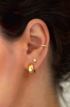 a close up of a person's ear wearing gold earrings