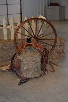 an old spinning wheel with hay on the ground