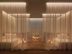 a bedroom with sheer curtains and candles on the floor