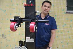 a man standing next to a machine with wheels on it's back and arms