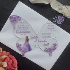 a butterfly shaped wedding card on top of a white piece of paper with purple flowers