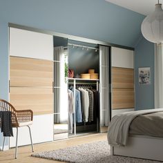 a bedroom with a bed, chair and closet in the corner next to a window