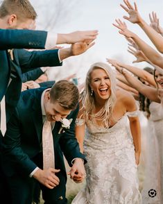 a bride and groom are surrounded by their wedding party hands as they walk down the aisle