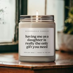 a candle with a quote on it sitting on a table next to a potted plant