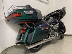 a green and black motorcycle is parked in a room with a white wall behind it