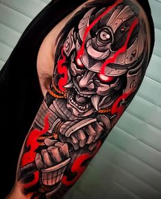 a man with a tattoo on his arm holding a knife and wearing a helmet that has red flames coming out of it