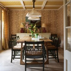 the dining room table is surrounded by chairs and vases with flowers in them,