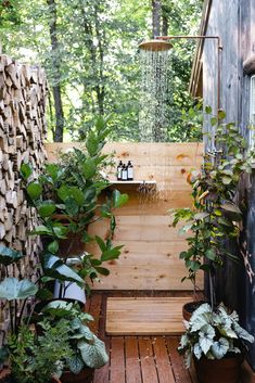 an outdoor shower surrounded by plants and wood