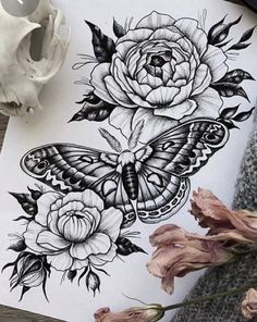 some flowers and a butterfly on a piece of paper next to a vase with a skull